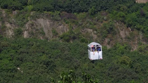 Close-up of several people on a cable car between mountains and green trees in t 動画素材 198760946