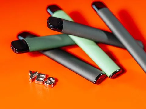 A close-up of several sleek e-cigarettes in shades of black and green. Stock Photos