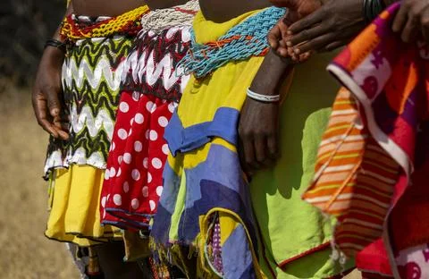 Close-up of several women's colorful patterned skirts and beaded waistbands.. 库存照片