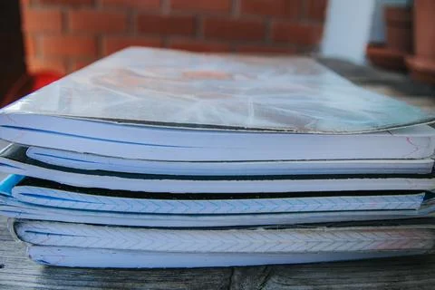 Close-up of several worn notebooks stacked on a wooden surface. Stock Photos