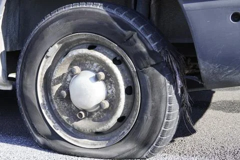 A close-up of a severely damaged and flat car tire. Stockfoto's