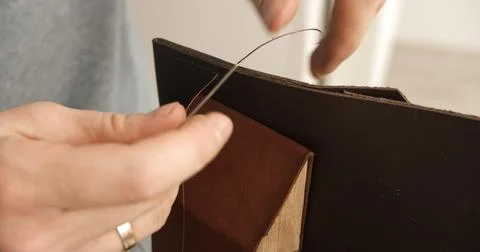 Close-up of sewing brown leather edge with thread during handmade bag crafting Stock Photos