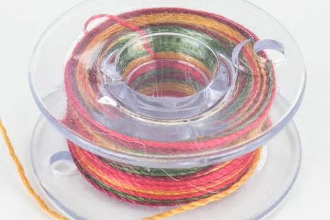 Close up of sewing machine bobbin with colourful thread, white background Stock Photos
