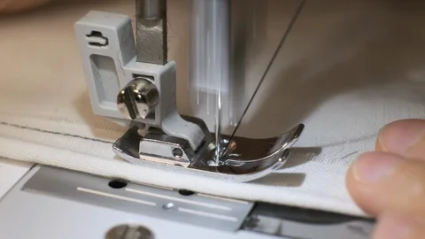 Close-up of sewing machine needle rapidly moves up and down. White fabric Stock Footage 114621572