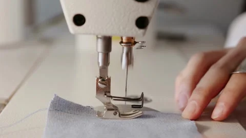 Close-up of a sewing machine needle stitching light blue fabric Keywords: s.. Stock Footage 339163193