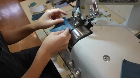 Close up of sewing machine stitching edge of teal leather piece Stock Footage 339652695