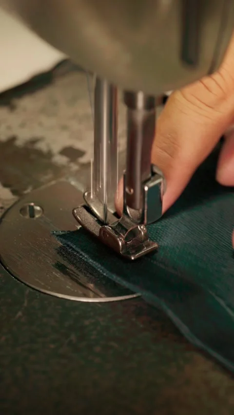 Close-up of a sewing machine stitching the end of a dark blue fabric seam, .. Stock Footage 342492019