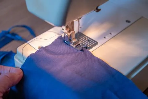 Close up of sewing machine stitching material to make a homemade face mask Stock Photos