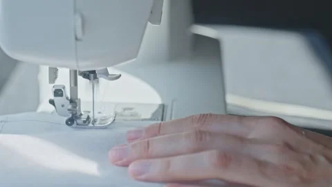 Close up of sewing machine stitching white fabric with hand guiding Stock Footage 316697600