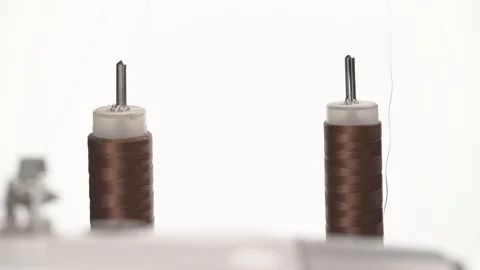 A close-up of a sewing machine in work. A spool of a high quality brown thread Stock Footage 105490777