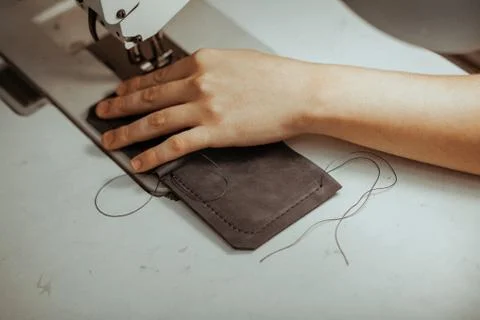 Close up of sewing machine working part with leather. The master's hands sews a Stock Photos