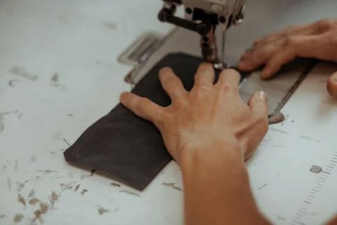 Close up of sewing machine working part with leather. The master's hands sews a Stock Photos