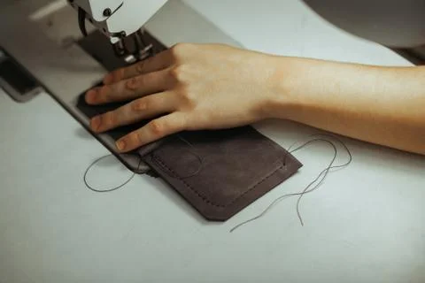 Close up of sewing machine working part with leather. The master's hands sews a Stock Photos