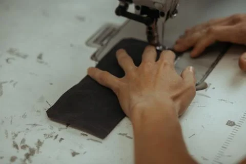 Close up of sewing machine working part with leather. The master's hands sews a Stock Photos