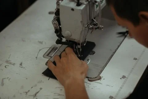 Close up of sewing machine working part with leather. The master's hands sews a Stock Photos