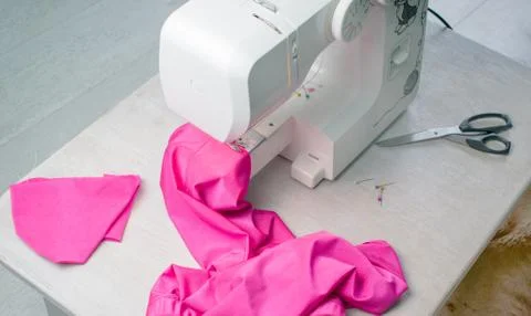 Close up of sewing machine working with pink fabric, scissors and pins on a t Stock Photos