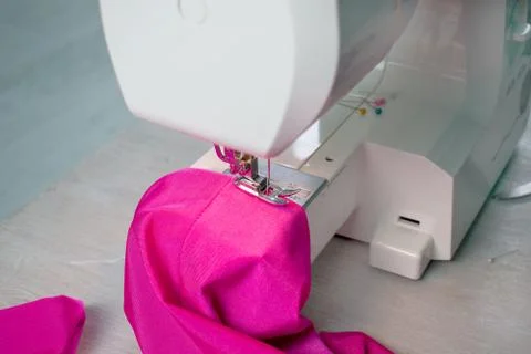 Close up of sewing machine working with pink fabric and pins on a table. Home Stock Photos