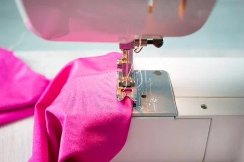 Close up of sewing machine working with pink fabric and pins on a table. Home Stock Photos