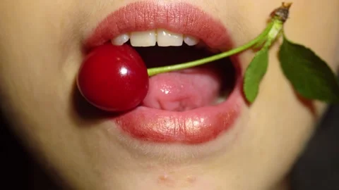 Close-up of sexy lips tasting a fresh cherry. Macro shot of mouth. Cherry 動画素材 321276957
