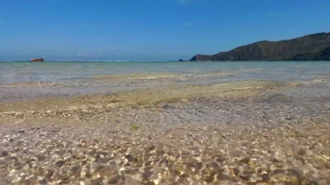 Close up shallow and gentle beach waves with blue sky and island. Stock Footage 280032306