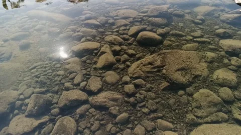 Close up of shallow clear water over pebbled riverbed with ripples 库存影片 345569687
