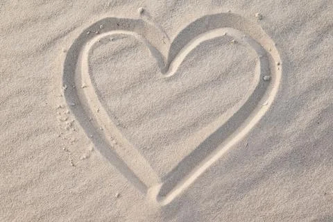 Close up of shape of heart drawn on wavy sand Stock Photos