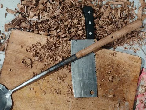 Close up of a sharp carving knife and wood shavings on a wooden workbench. Stock Photos