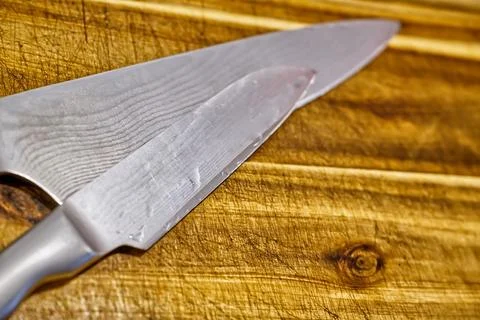 Close-up of a sharp kitchen knife resting on a wooden cutting board, showcasi Stock Photos