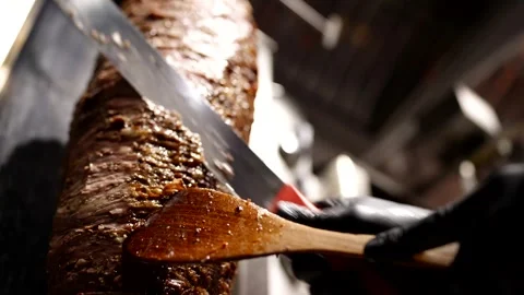 Close-up of sharp knife slicing juicy layers of grilled shawarma meat under  Vídeo Stock 310929615