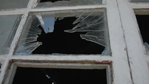 Close-up of a shattered window in an old abandoned building, revealing jagged Stock Footage 337776630