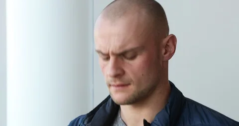 Close up of shaved head male looking out window putting on glasses Stock Footage 89462282