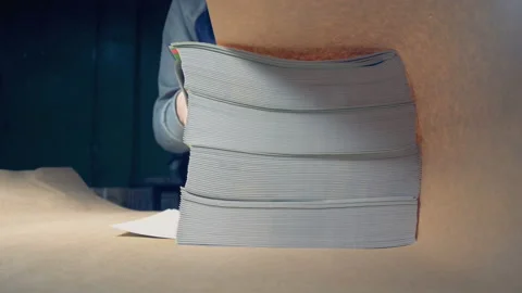 Close up of a sheaf of magazines being wrapped up into paper and carried away Video stock 88801463