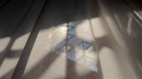 Close up of sheer curtain with hexagonal window frame casting sharp shadow .. Stock Footage 314607628