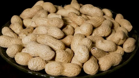Close-up of shelled peanuts rotating on a glass plate. Black background. Stock Footage 304421898
