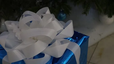 A close-up of a shiny blue gift box adorned with a large white ribbon Stock Footage 295139029