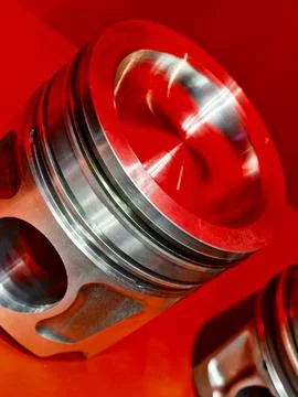 Close-up of a shiny engine piston displayed against a vibrant red background Stock Photos