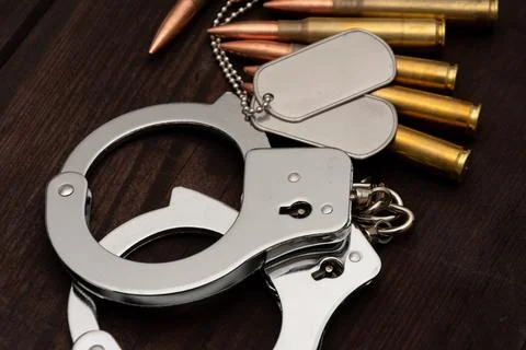 A close-up of shiny handcuffs, two army badges and several cartridges. The Stock-Fotos