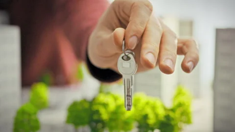 A close-up of shiny keys in a mans hand against a backdrop of miniature resi Stock Footage 341490596