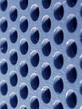 Close-up of shiny perforated metal surface with blurred background and patt.. Foto stock