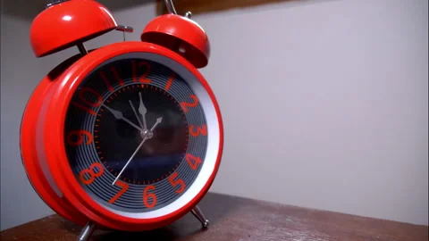 Close-Up of a Shiny Red Retro Alarm Clock on a Wooden Table Stock Footage 336696038