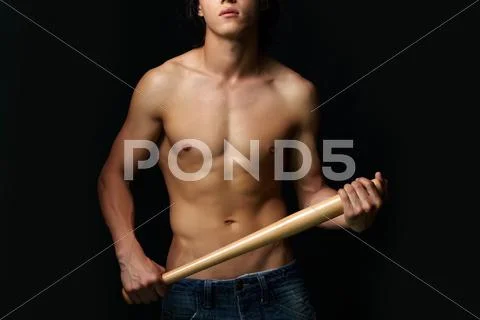 Close-up of shirtless man with bat over black background Stock Photos