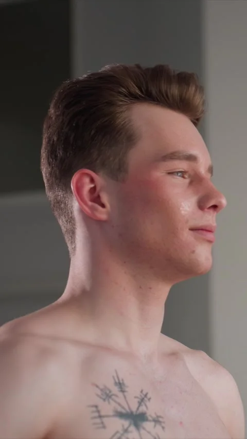 Close up of shirtless young man with brown hair tattoos against gray background Stock Footage 345667767