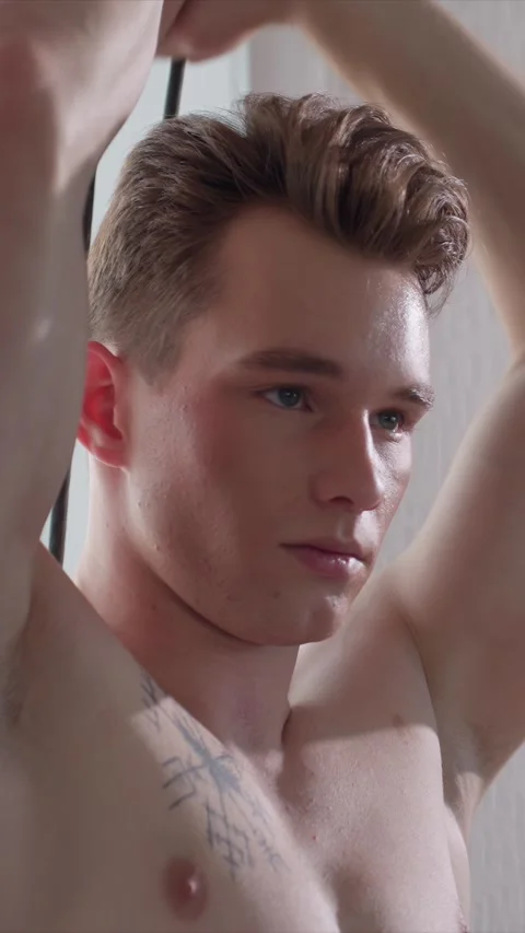Close up of shirtless young man with tattoos styling wet hair in plain indoor Stock Footage 343085211