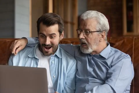 Close up shocked two generations of men looking at laptop Stock Photos