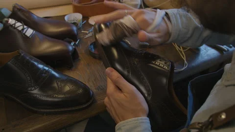Close up shoe manufacturing workshop. Shoemaker rubs shoes with cream sews shoes Stock Footage 137574471
