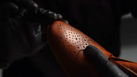 Close-up of shoemaker in black gloves rubbing paint on toe cup of brown leather Stock Footage 150070050