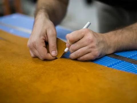 Close up of a shoemaker cutting leather in a workshop. Handmade leather craft Stock Photos