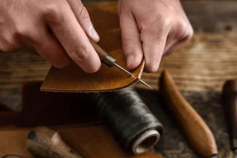 Close up of a shoemaker or artisan worker hands. Leather craft tools on old wood Stock Photos