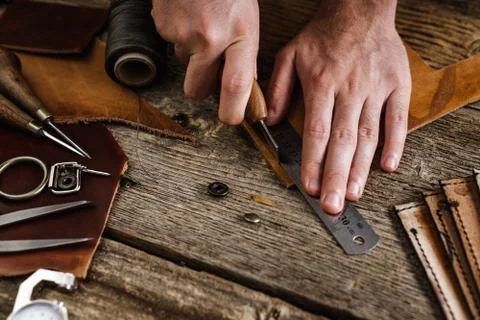 Close up of a shoemaker or artisan worker hands. Leather craft tools on old wood Stock Photos