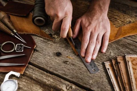 Close up of a shoemaker or artisan worker hands. Leather craft tools on old wood Stock Photos